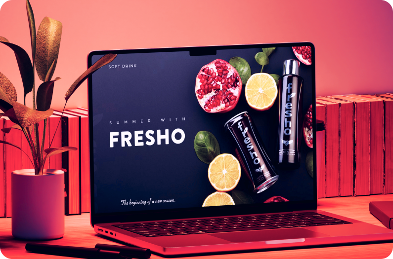 Laptop displaying FRESHO soft drink branding presentation with pomegranate and lemon slices on a vibrant pink background.